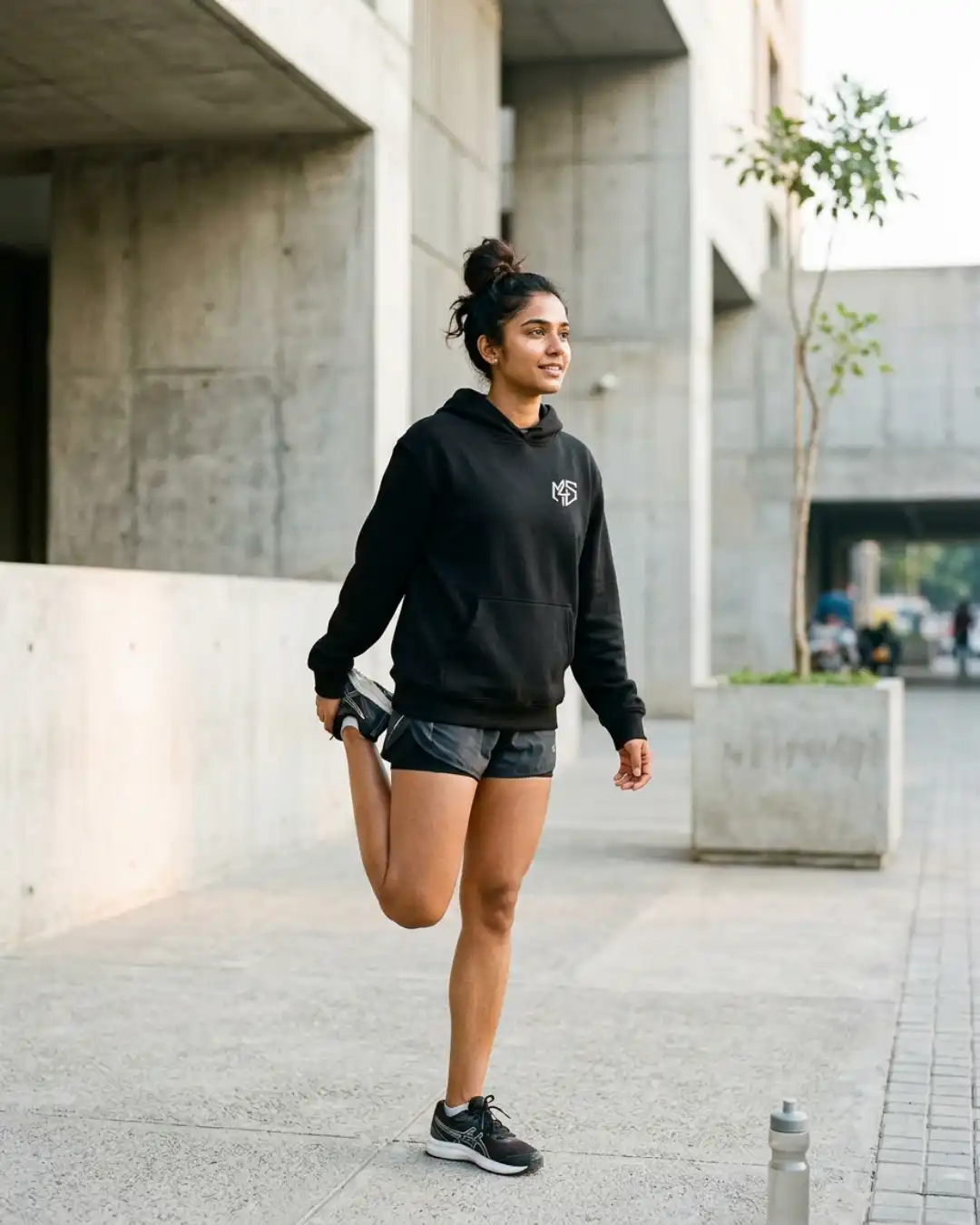 Off Autopilot Hoodie – Train – Running Woman wearing the Off Autopilot Hoodie while stretching during a run in an urban setting