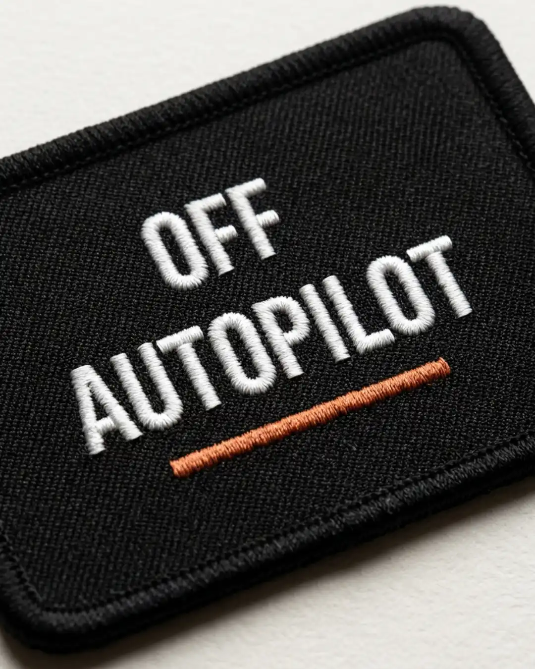Off Autopilot Patch – Embroidery Detail Close-up of the Off Autopilot patch showing embroidered lettering, orange underline and stitched border