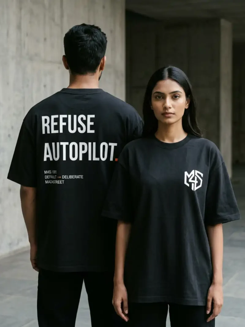 Male and female models wearing the black Refuse Autopilot Heavyweight Oversized Tee in an urban setting